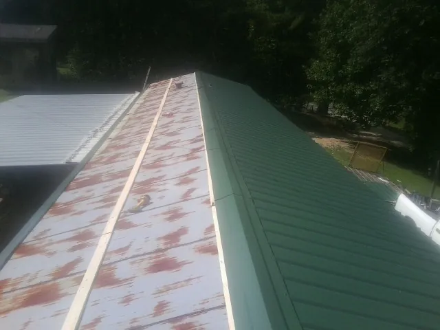 Old rusted panels beside newly installed green metal roofing — Wind Damage Roof Repair by Roofing Brothers in Lutz