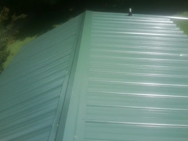 New green metal panels meeting at the ridge of a roof — Flat Roof Repair work by our crew in Lutz