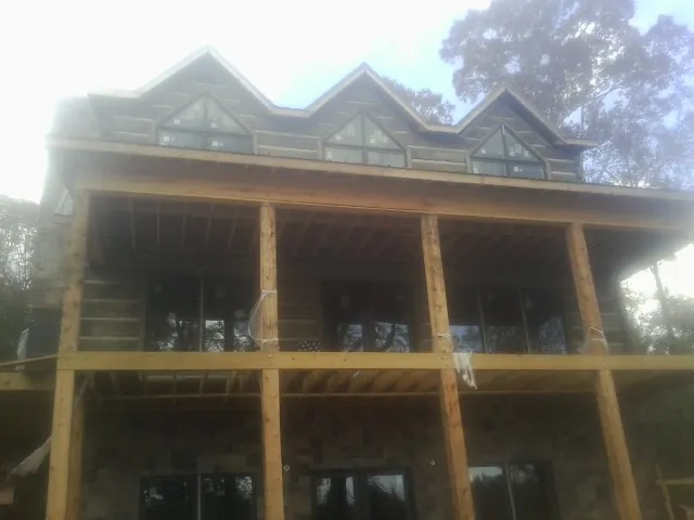 Dormers and porch framing on a large log home under construction — Roof Coating work by our crew in Lutz