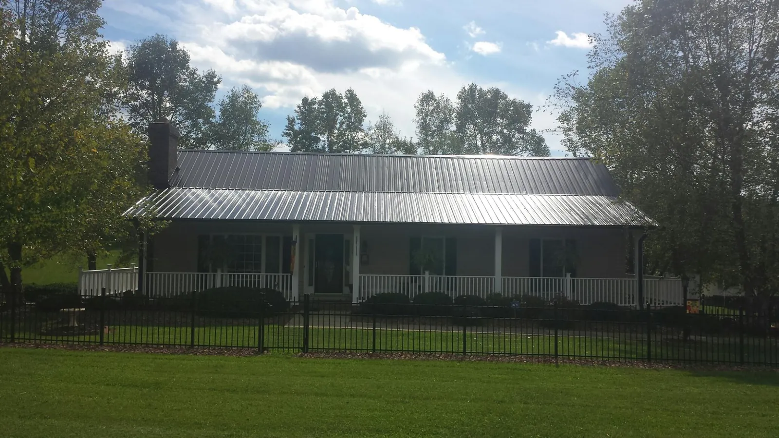 Gray metal roof on a brick ranch with a full width front porch — Gutter Guard Installation work by our crew in Lutz