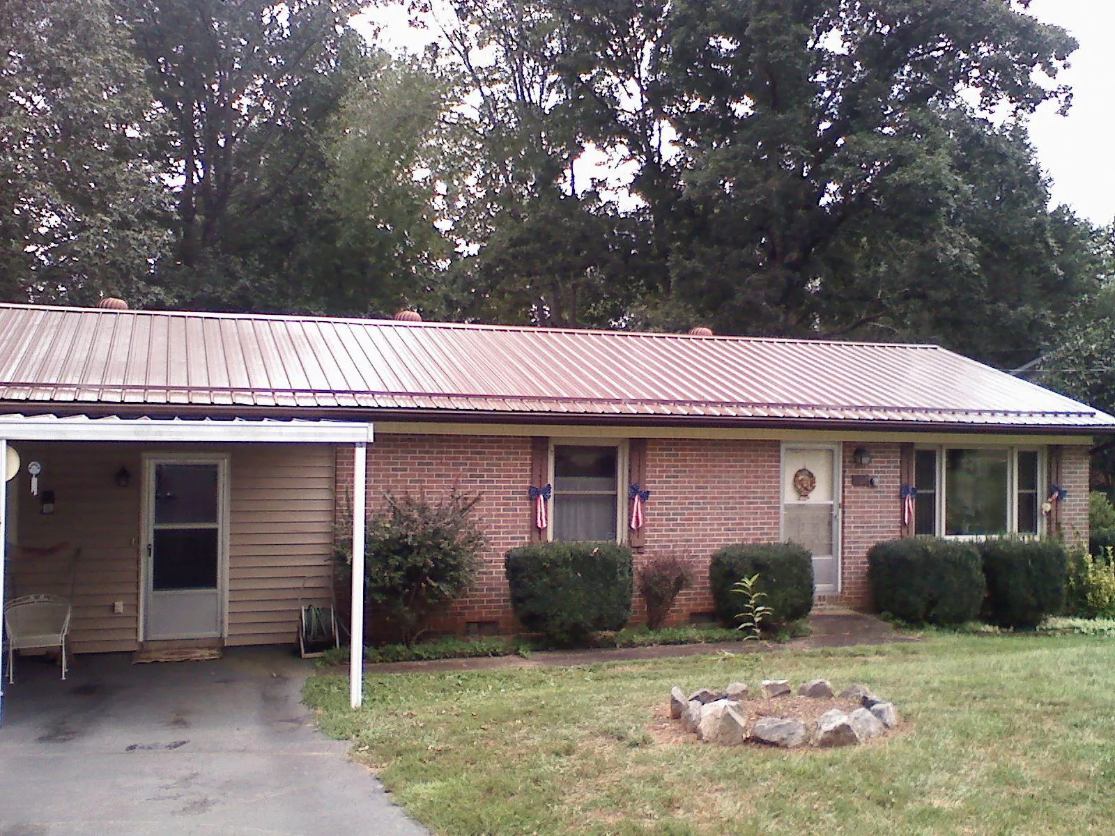 Bronze metal roof and carport on a brick ranch home — Roof Repair work by our crew in Lutz